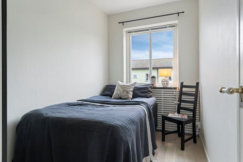 Separat sovrum med fönster, dörr och förvaring.