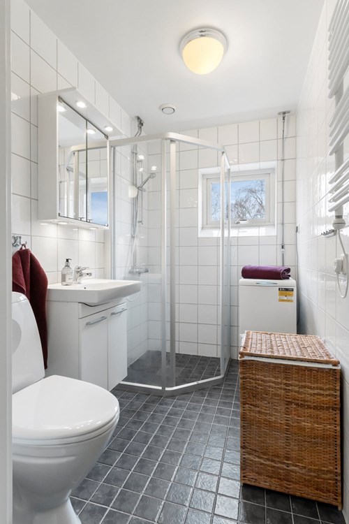 Mycket fräscht badrum med toppmatad tvättmaskin.